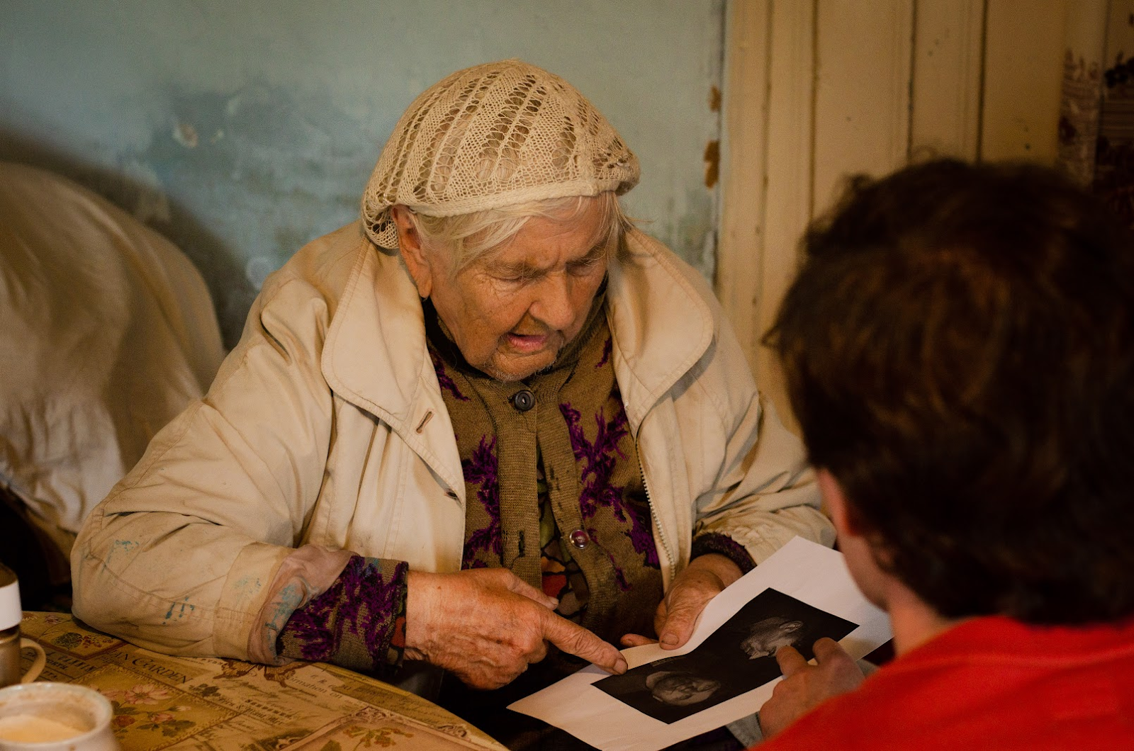 Любовь Тупицина рассматривает фото отца на распечатке из архива